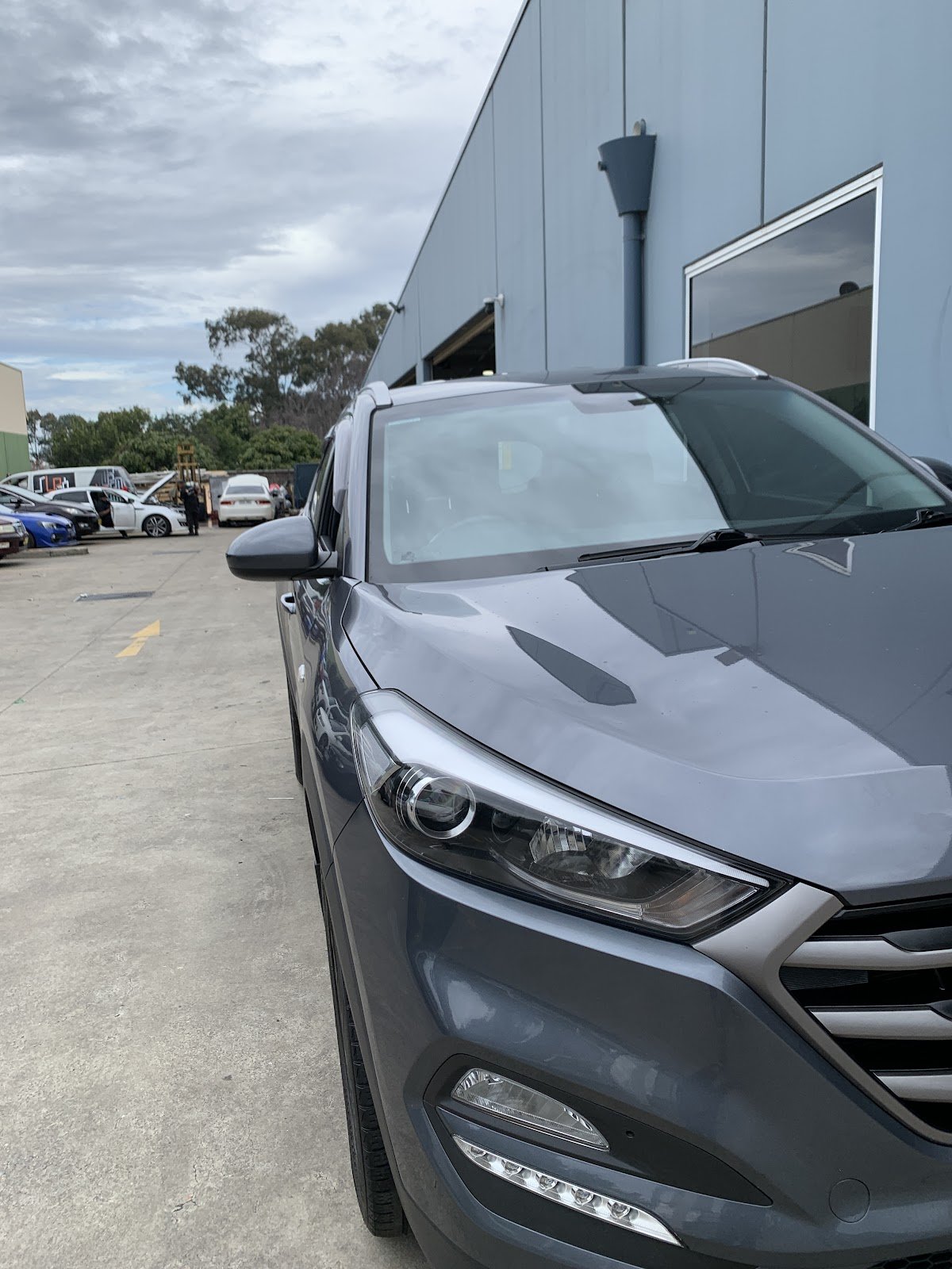 Cars parked in the yard outside LP Automotive on Gilba Rd, Girraween, with the workshop roller door open